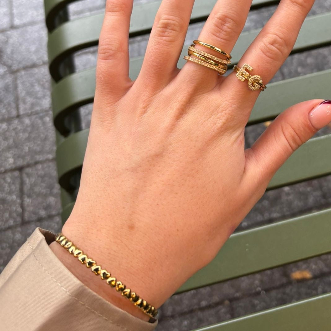 Hand with gold rings on a green metal bench