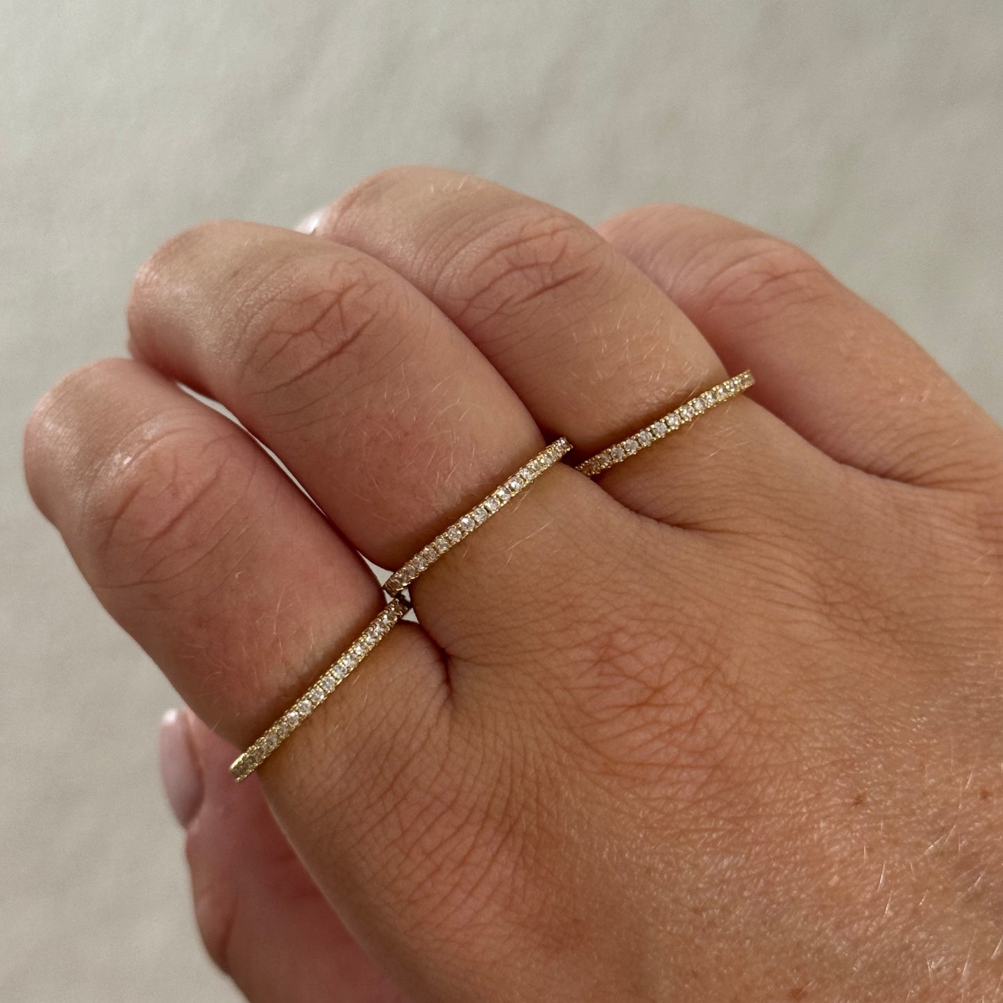 Close-up of a hand wearing a gold ring on a neutral background