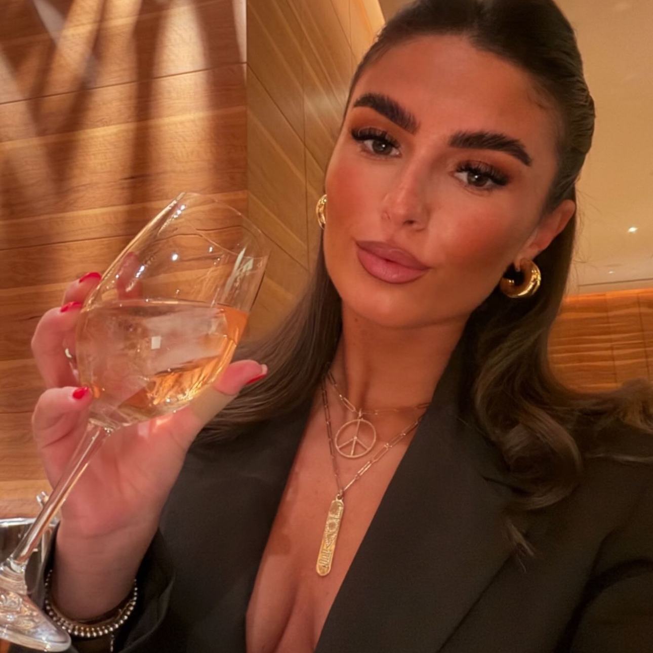 Woman holding a glass of wine indoors with warm lighting