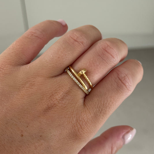 Hand wearing two gold rings on a neutral background